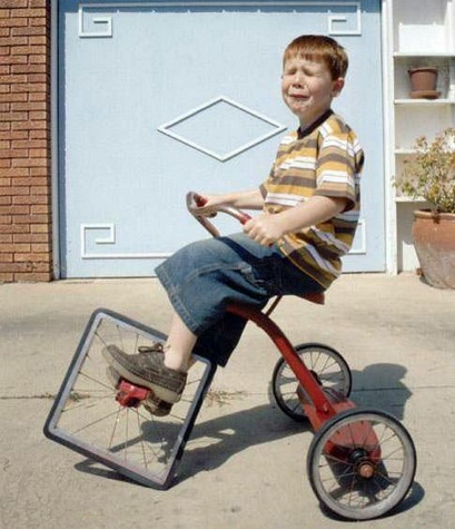 Crying ginger boy driving a tricycle with a square wheel