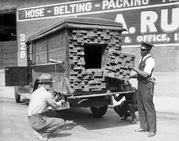A federal agent inspects a 'lumber' truck after smelling alcohol during the prohibition period, Los Angeles, 1926.