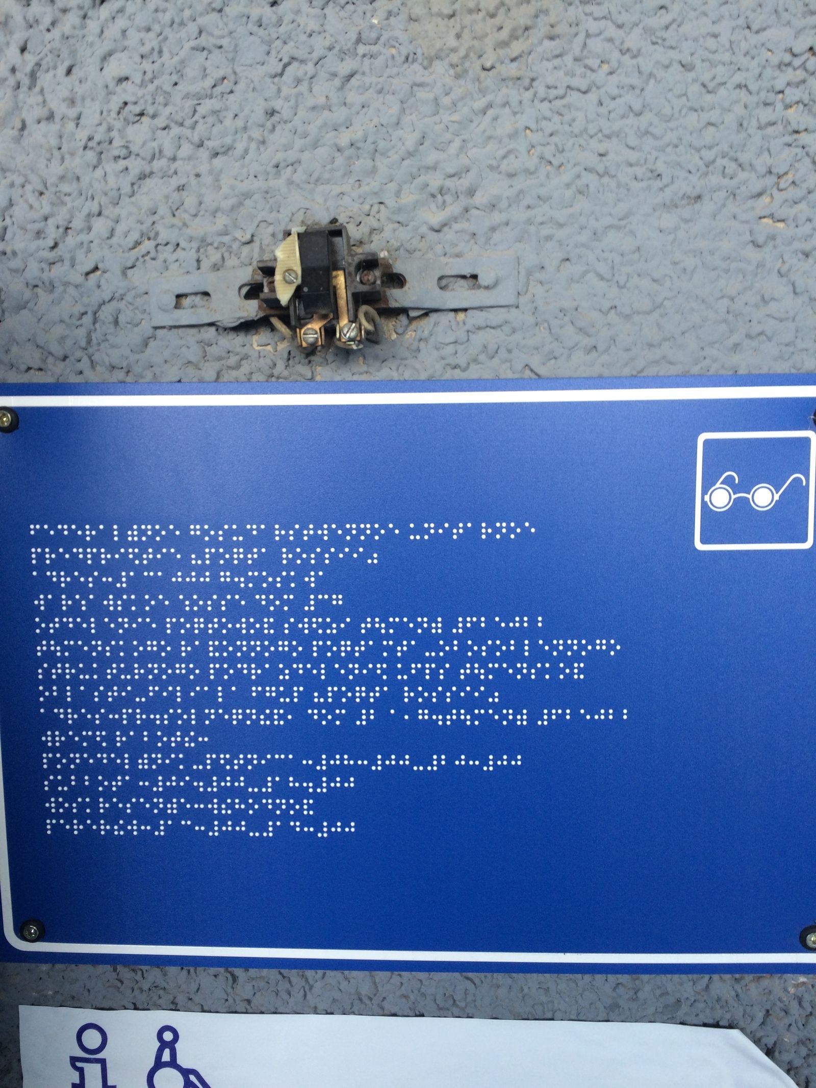 A signboard for the blind next to bare wire