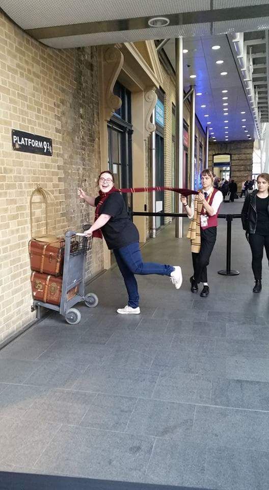 The girl working platform 9 3/4 is really tired of adult children posing for pictures.