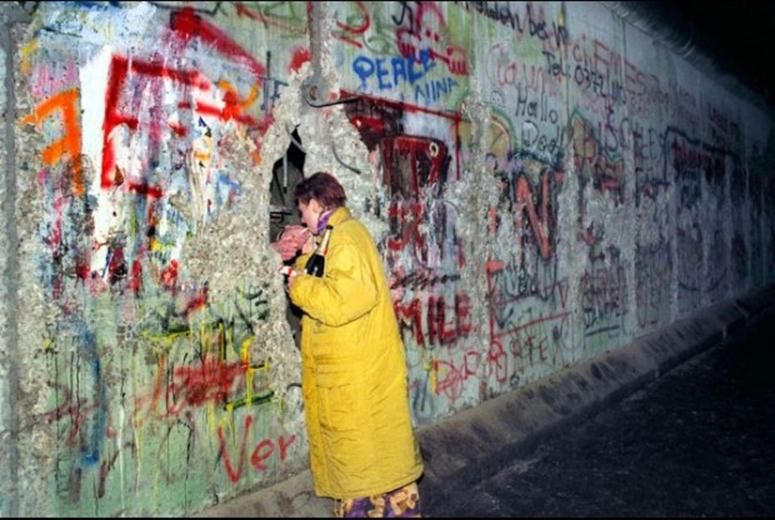 A man secretly lights a woman’s cigarette through the Berlin wall, 1989