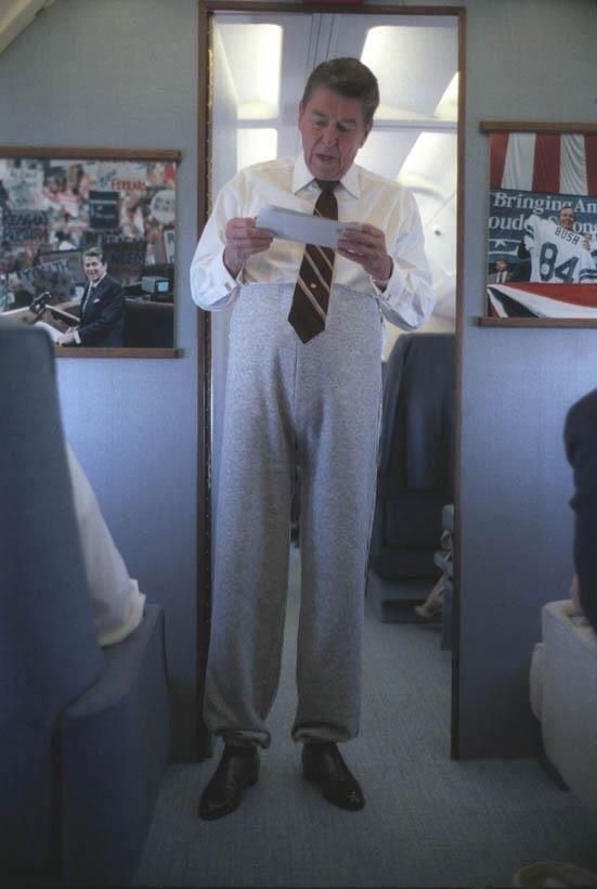 Ronald Reagan wearing sweatpants talking to staff aboard Air Force One on a trip to Iowa, September 1984.