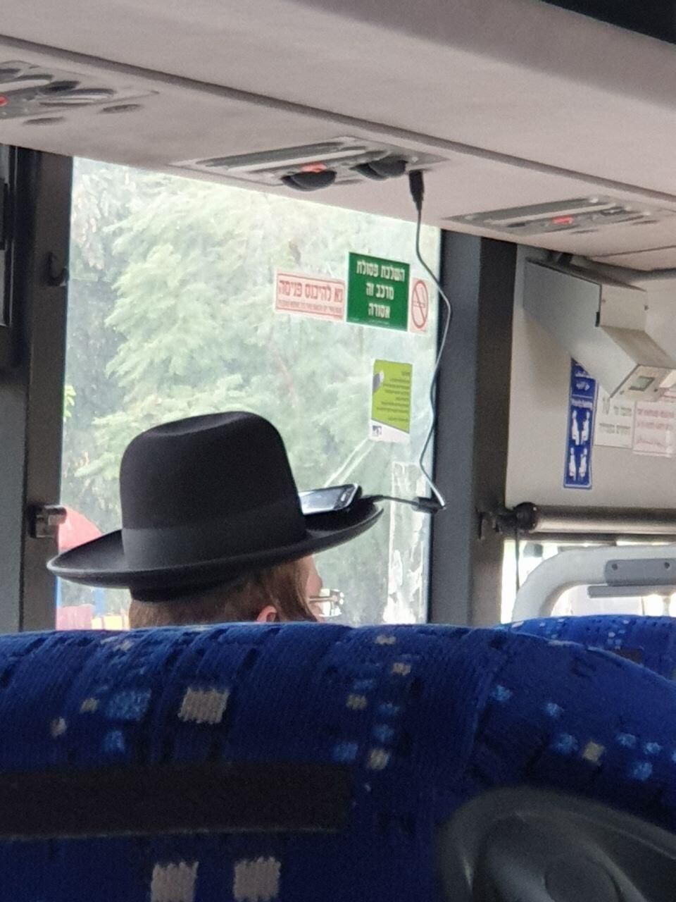 Guy charging his phone on the bus