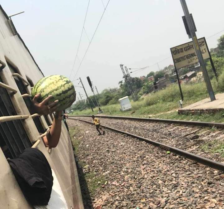 A guy bought this watermelon from a vendor while the train made a quick stop. He had to hold it like this because it didn't fit between the bars and the train resumes it's journey.