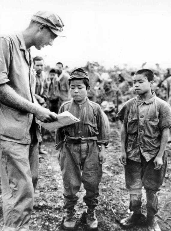 An American Marine shows Japanese kids how to draw anime, June 1945.