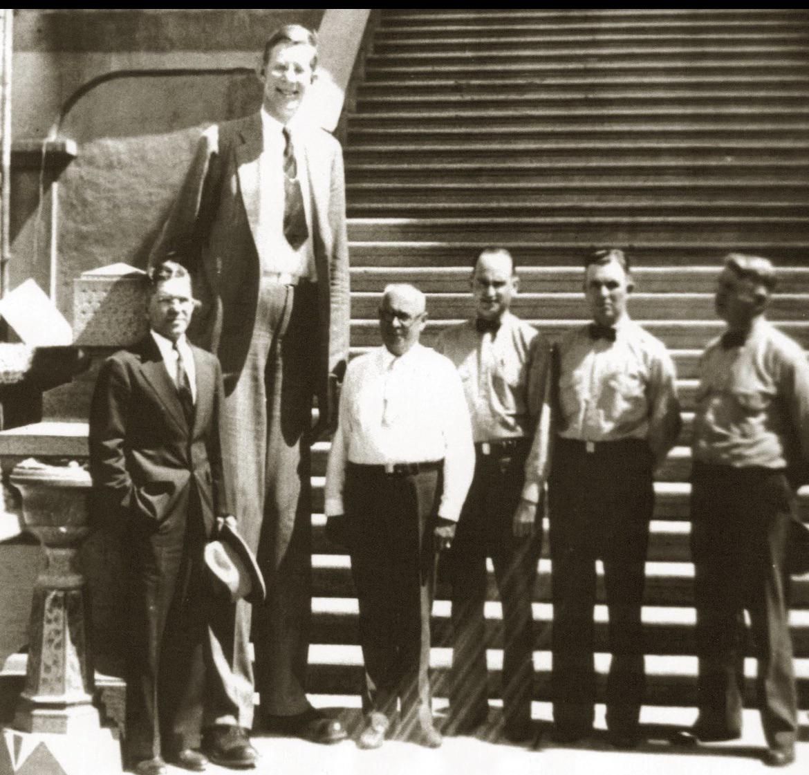 The World's First 6-foot Tall Man standing next to 5'11" men,